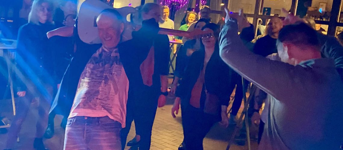 gitarrist spielt gitarre hinterm kopf im tanzenden publikum