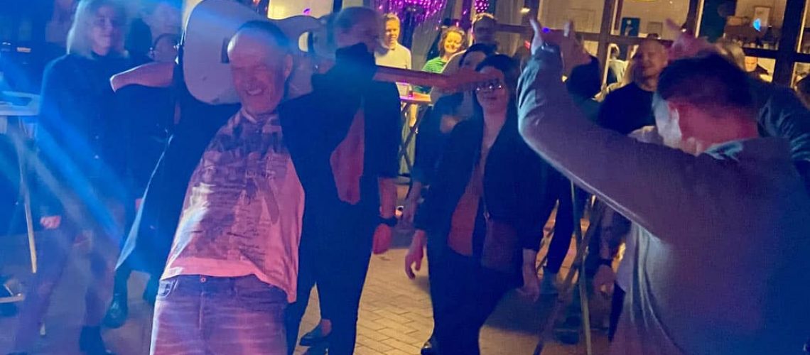 gitarrist spielt gitarre hinterm kopf im tanzenden publikum